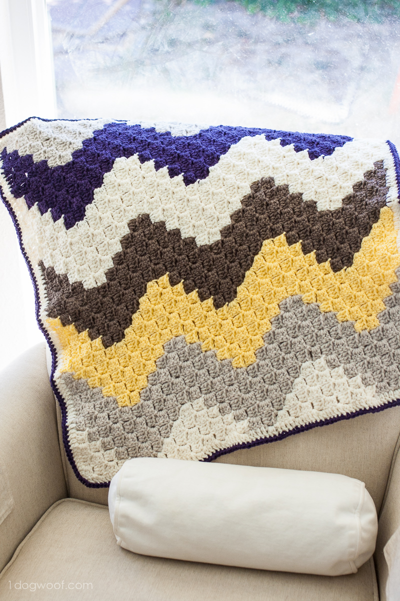c2c chevron crochet blanket on an armchair with tubular pillow
