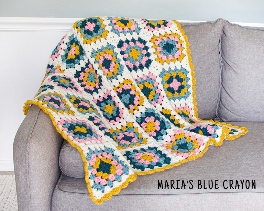granny square crochet blanket on a grey sofa