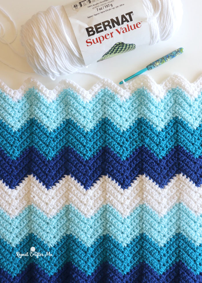 easy chevron crochet blanket next to a skein of white yarn and crochet hook