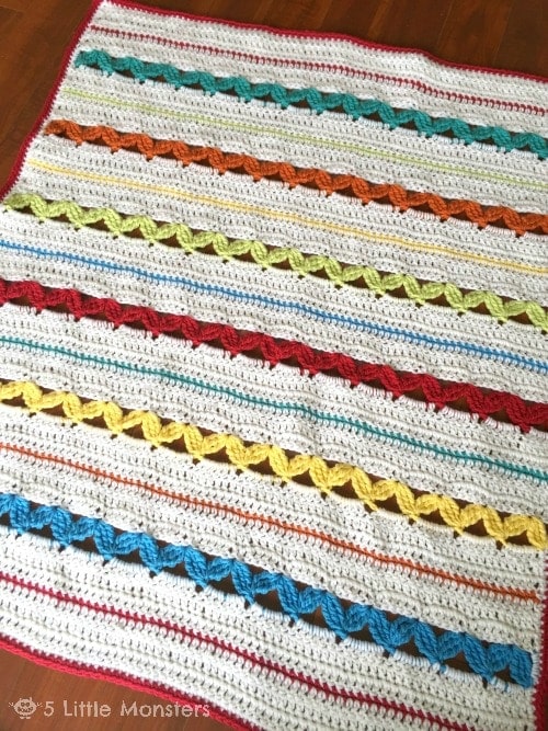 striped crochet blanket flat on a wooden floor