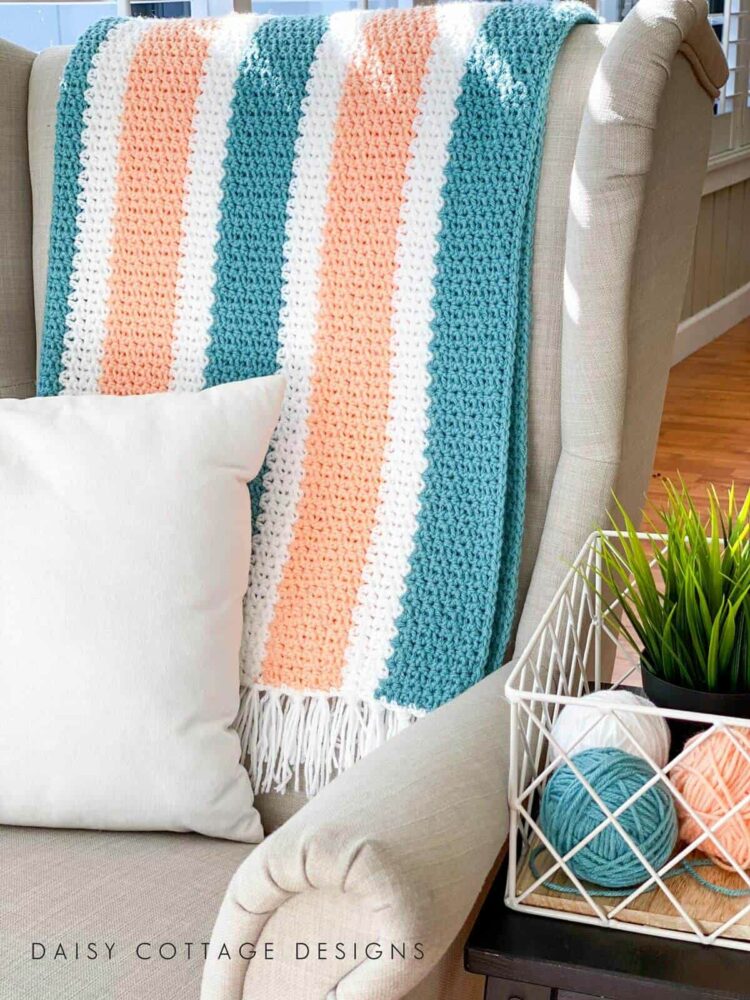 v-stitch easy crochet blanket on chair with balls of yarn